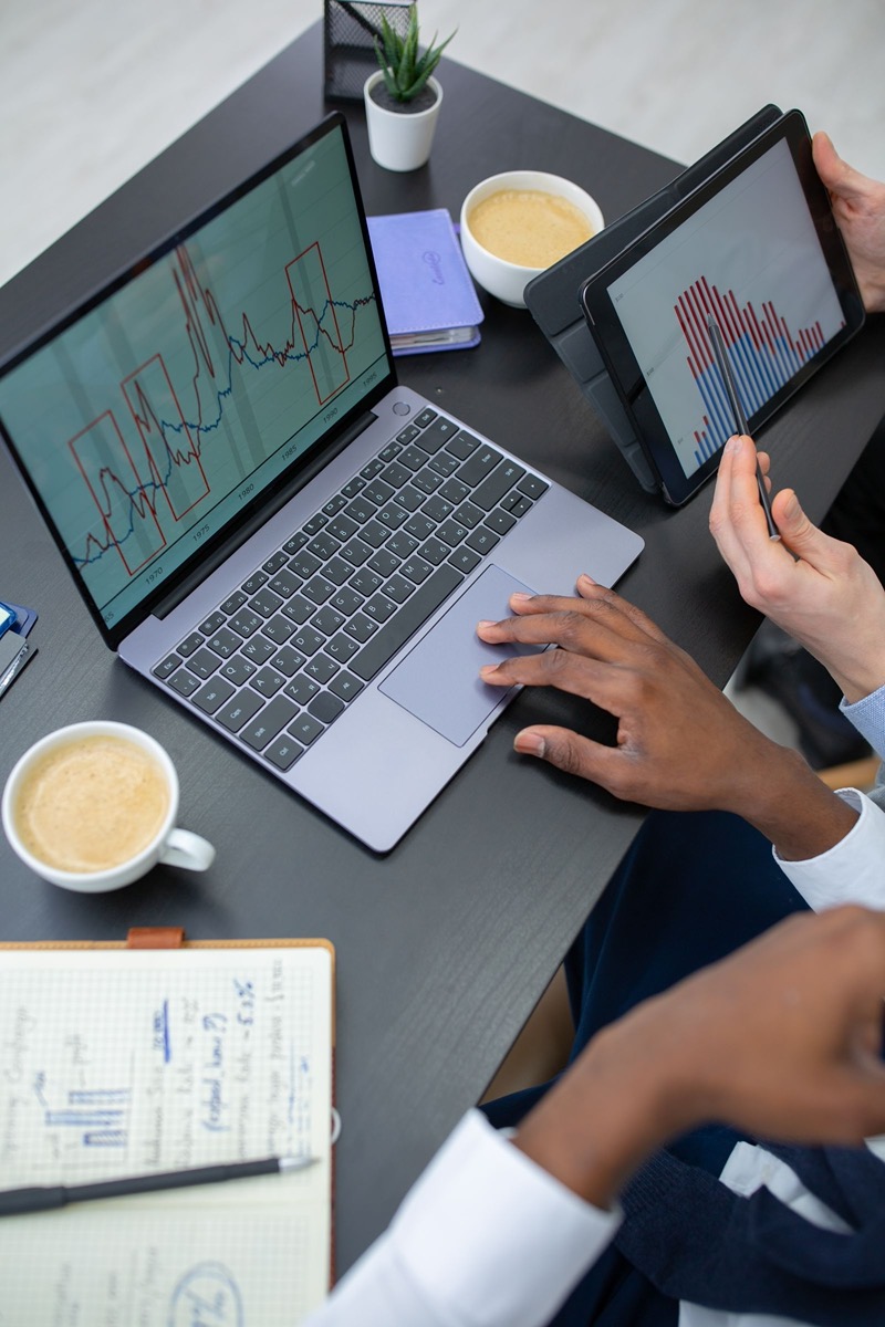 Mani su un portatile con un grafico di anomalie e su un tablet con grafici a barre, durante un'analisi dei dati