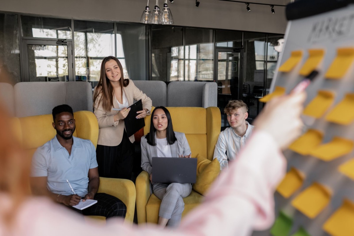 Quattro persone in una riunione di lavoro davanti a una parete di note adesive